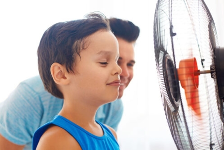 father & son standing in front of a fan