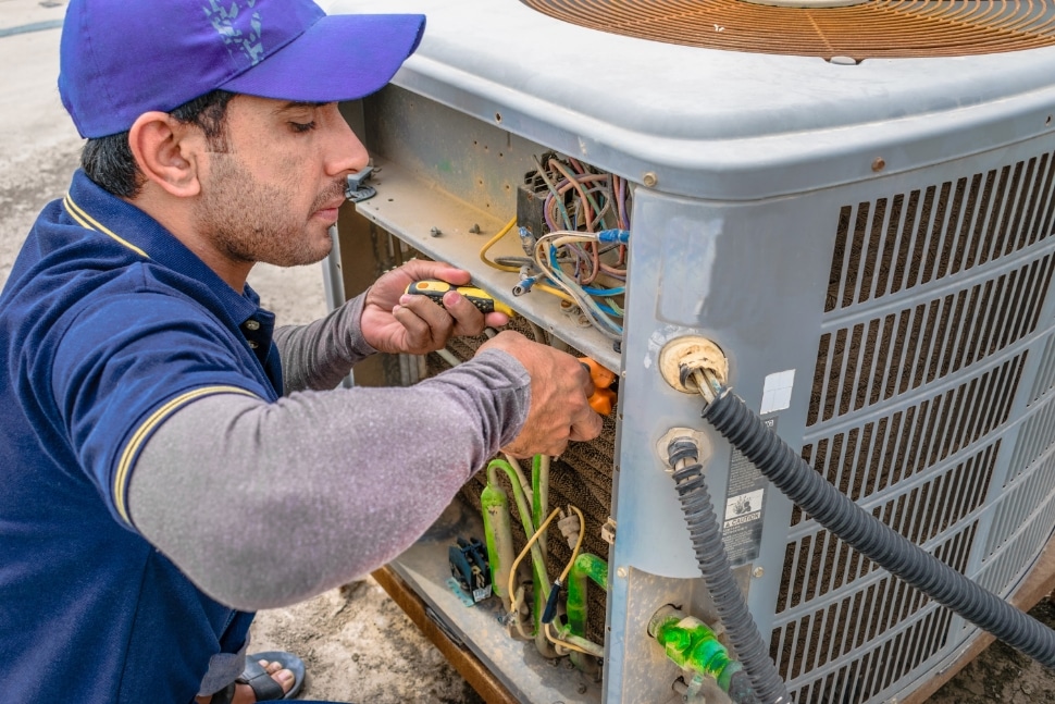 HVAC maintenance worker fixing an AC unit